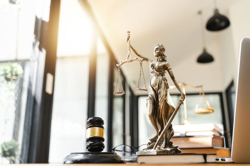 Lady justice statue and a gavel in bright sunlight room